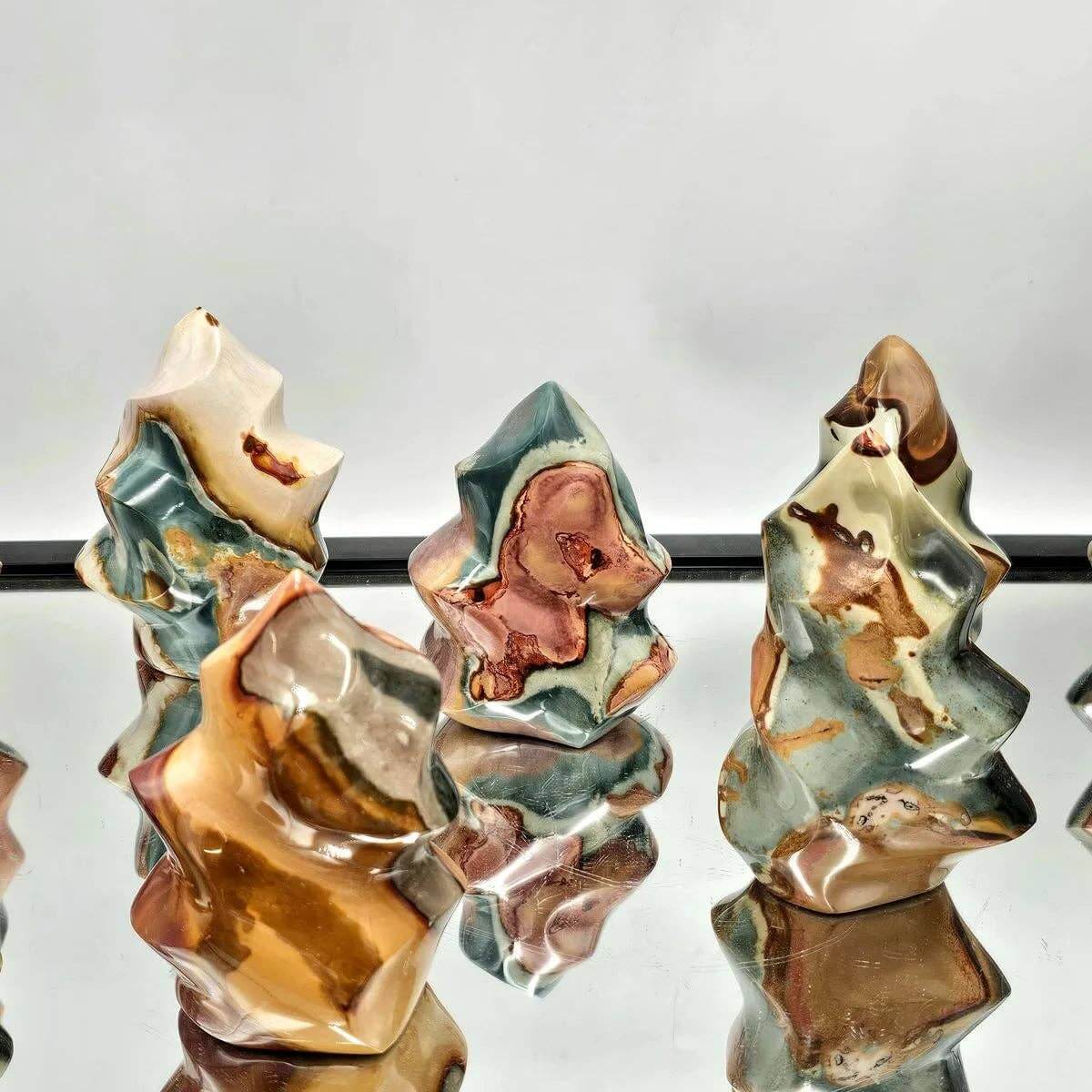 Three ceramic sculptures with earthy tones on a reflective surface
