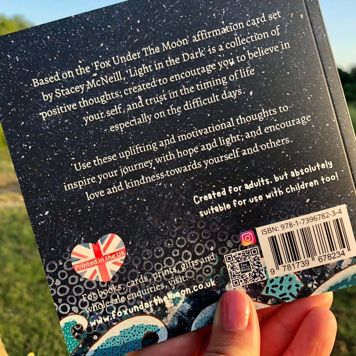 Back of a card with text and branding, held outdoors.