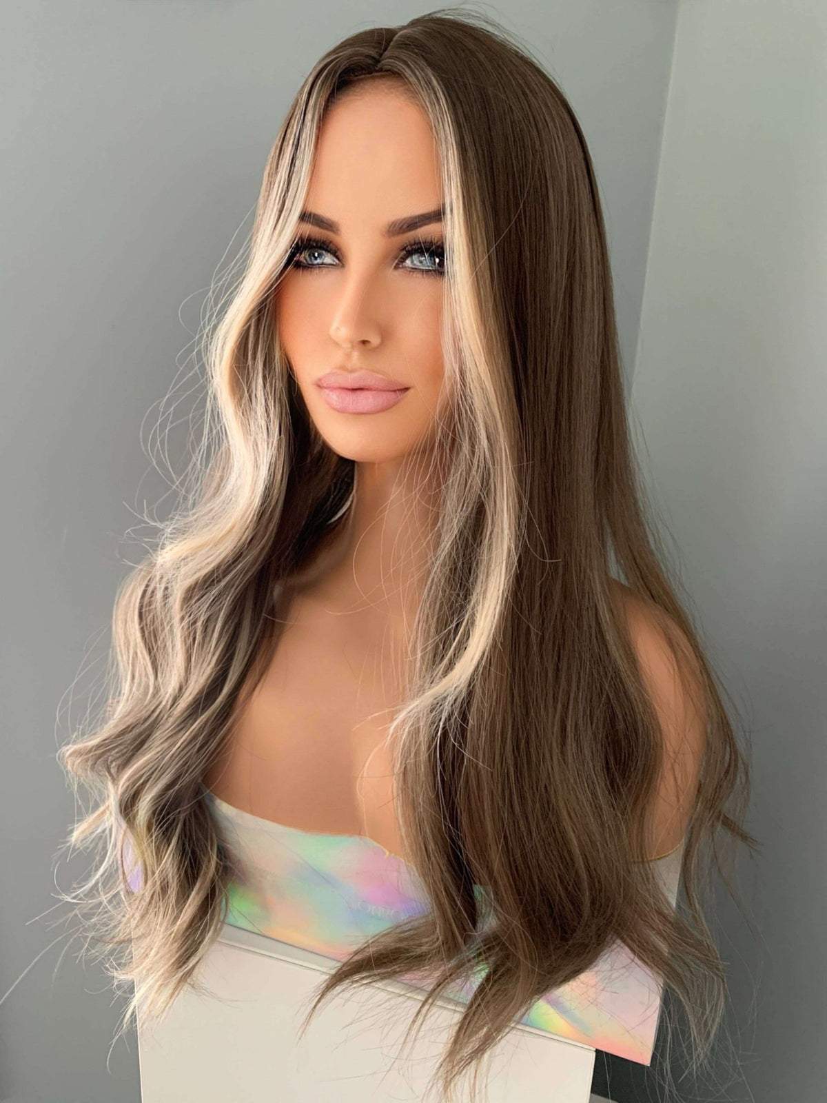 Person with long, wavy hair styled in a way that highlights the color transition from brown to blonde.