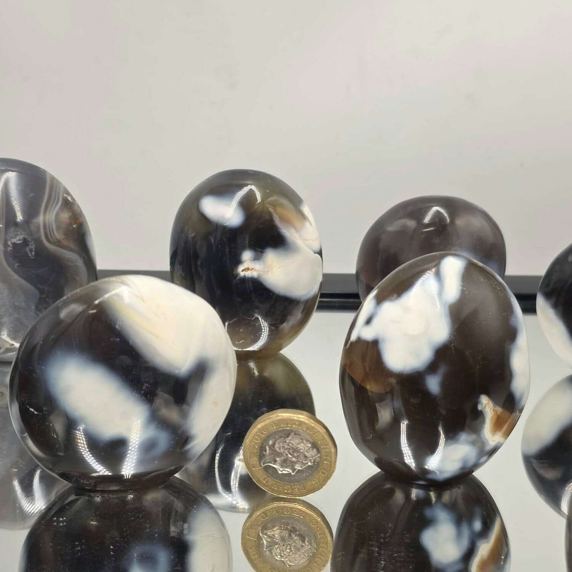 Black and white marbled beads on a reflective surface with a light gray background