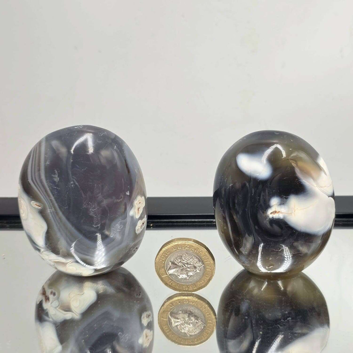 Three metallic objects on a reflective surface with coins below
