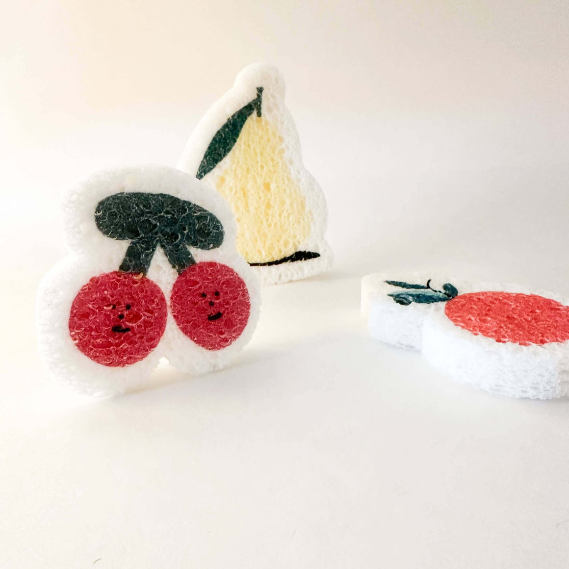 Two plush toys resembling a cherry and a slice of cake on a white background