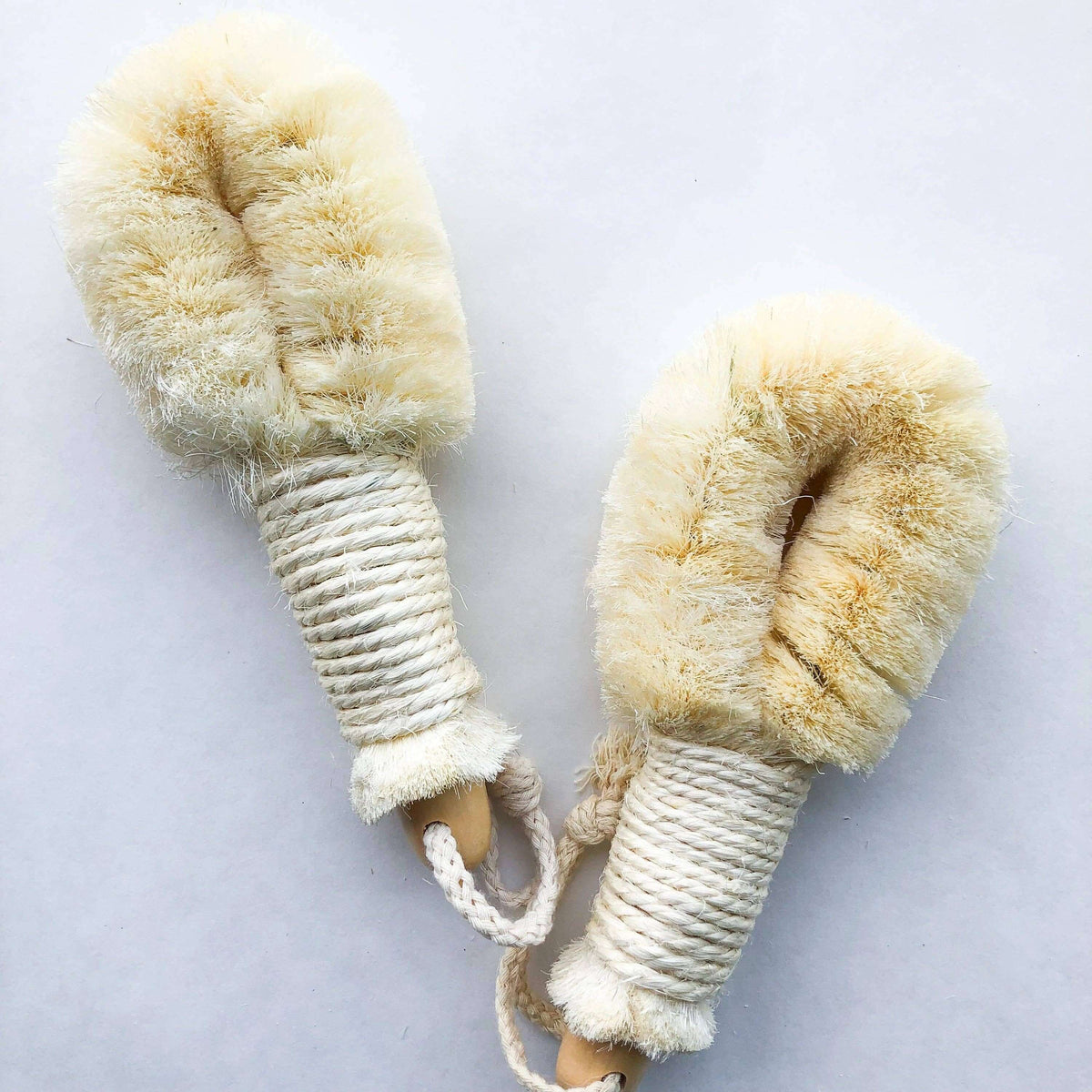 Pair of beige dog toys with rope handles on a light gray background