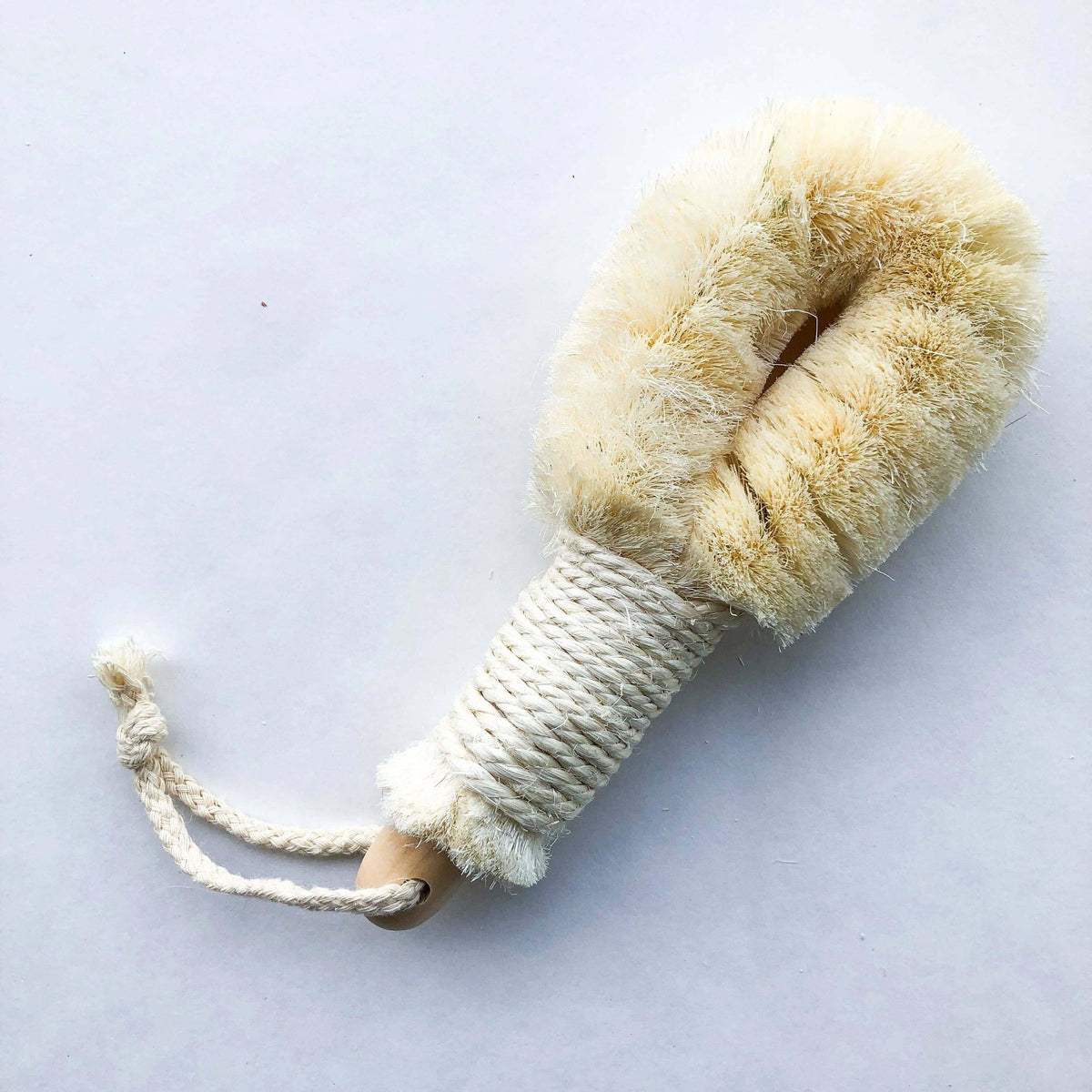 Natural fiber duster with a wooden handle on a light gray background