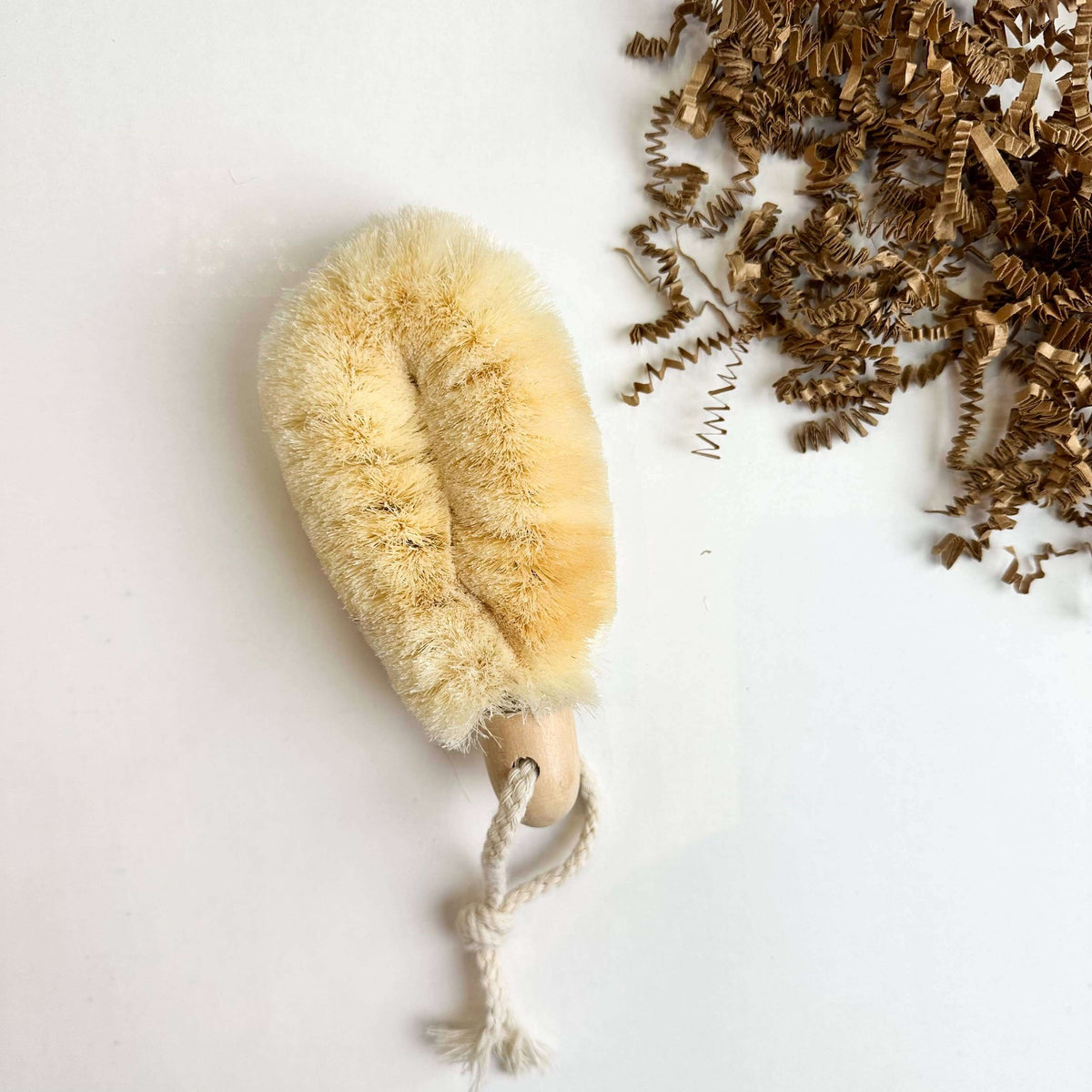 Beige natural brush with a rope handle on a white background