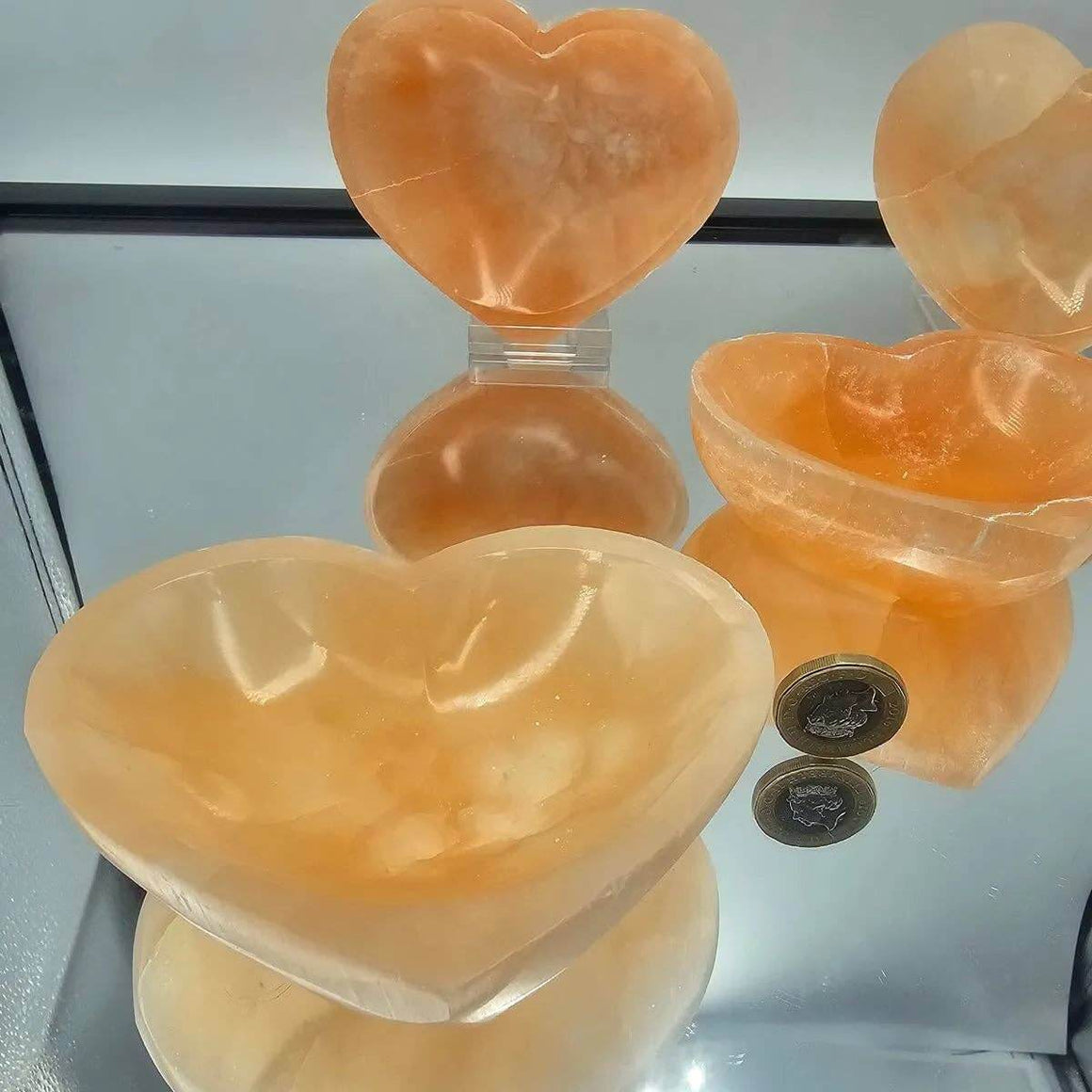 Heart-shaped orange stone bowls on a reflective surface