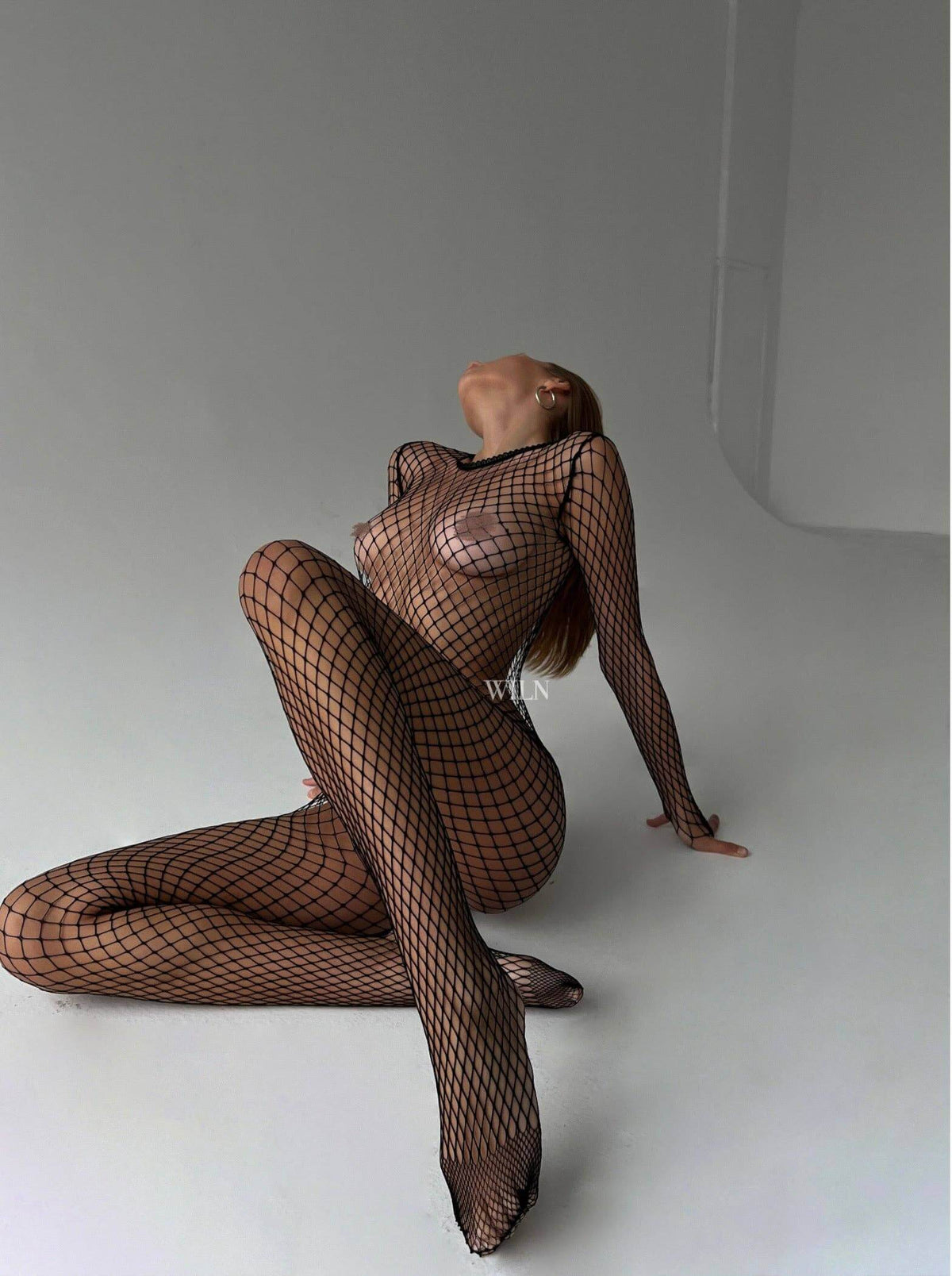 Model showcasing the PREY Fishnet Bodysuit in black, emphasizing its figure-hugging and sculpting design.