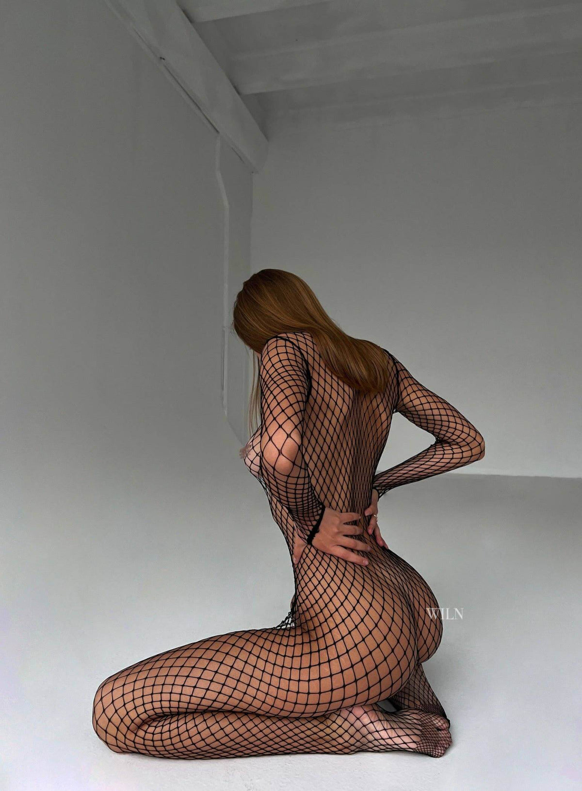 Model showcasing the PREY Fishnet Bodysuit in black, highlighting its figure-hugging design and stylish fishnet material.