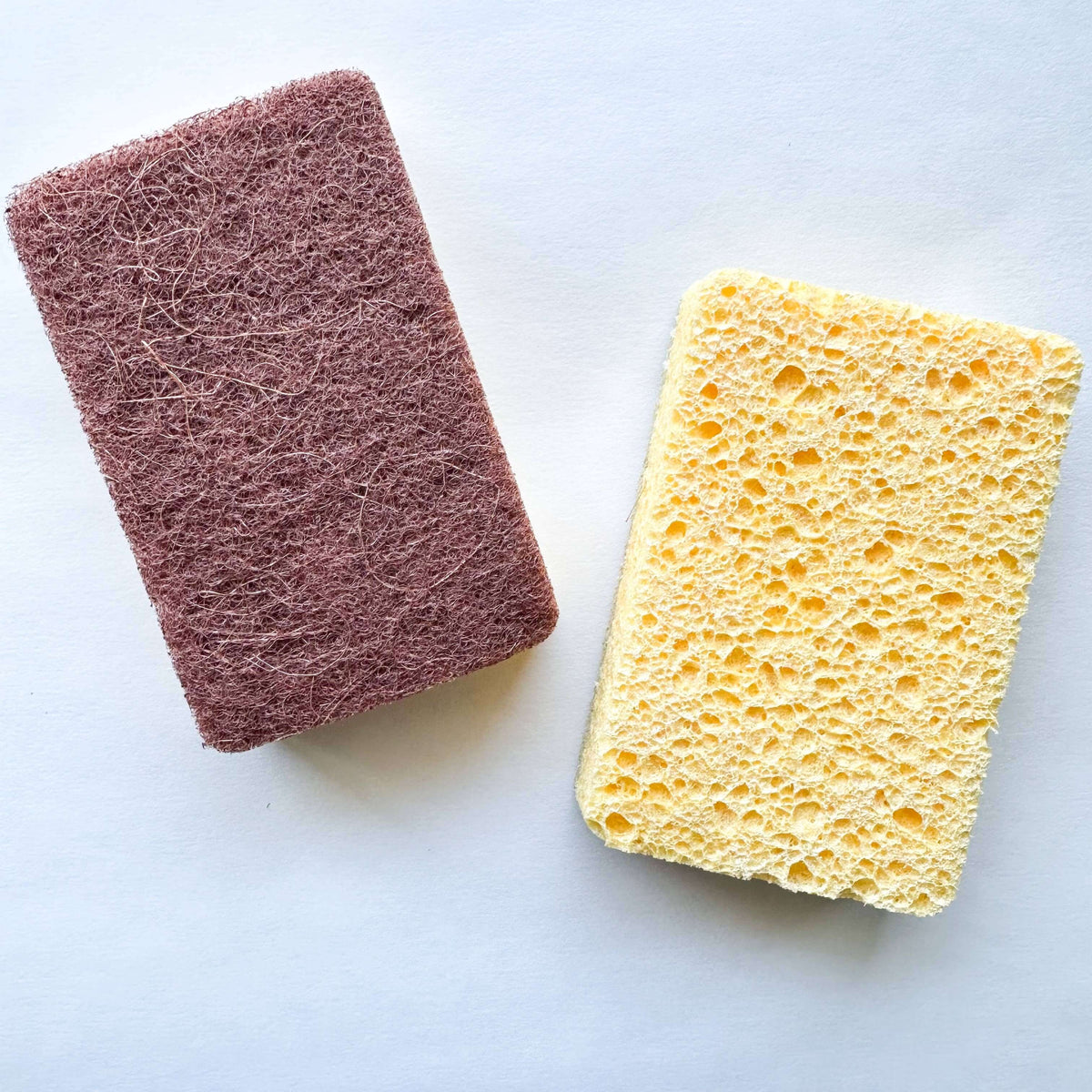 Purple scrubber and yellow sponge on a white background