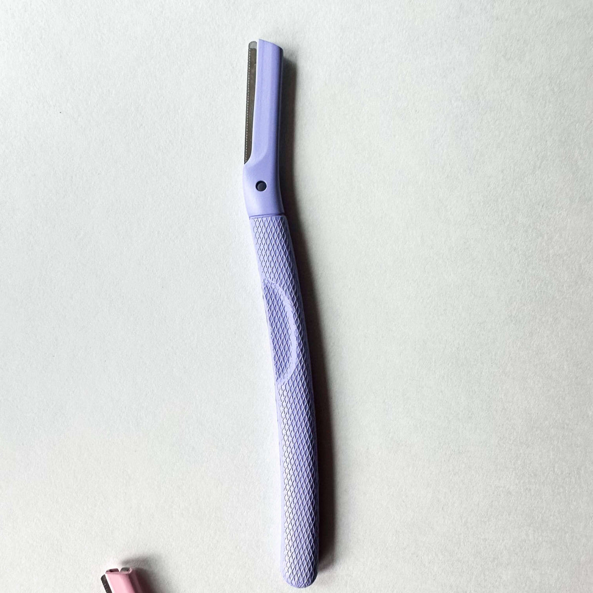 Purple facial razor on a light gray background