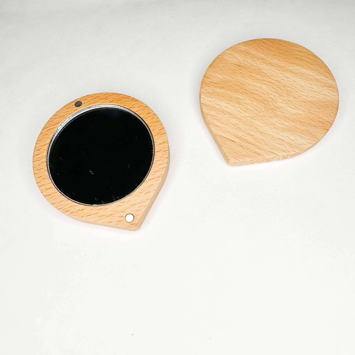 Wooden round mirror and black circular object on a white background