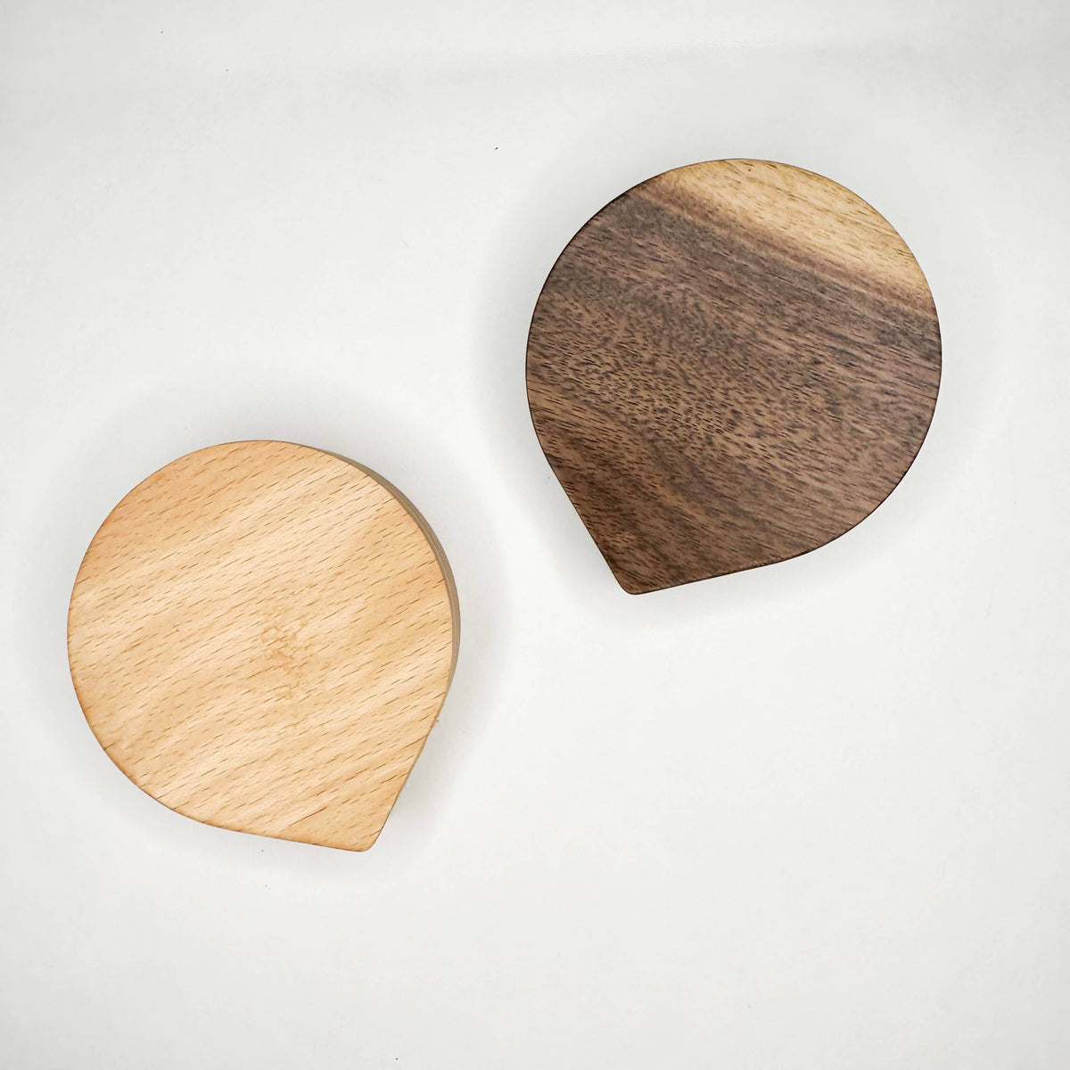 Two wooden coasters, one light wood and one dark wood, on a white background.