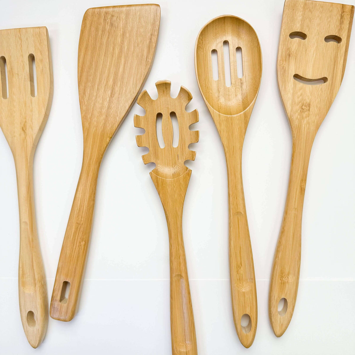 Set of five wooden kitchen utensils with different shapes on a white background