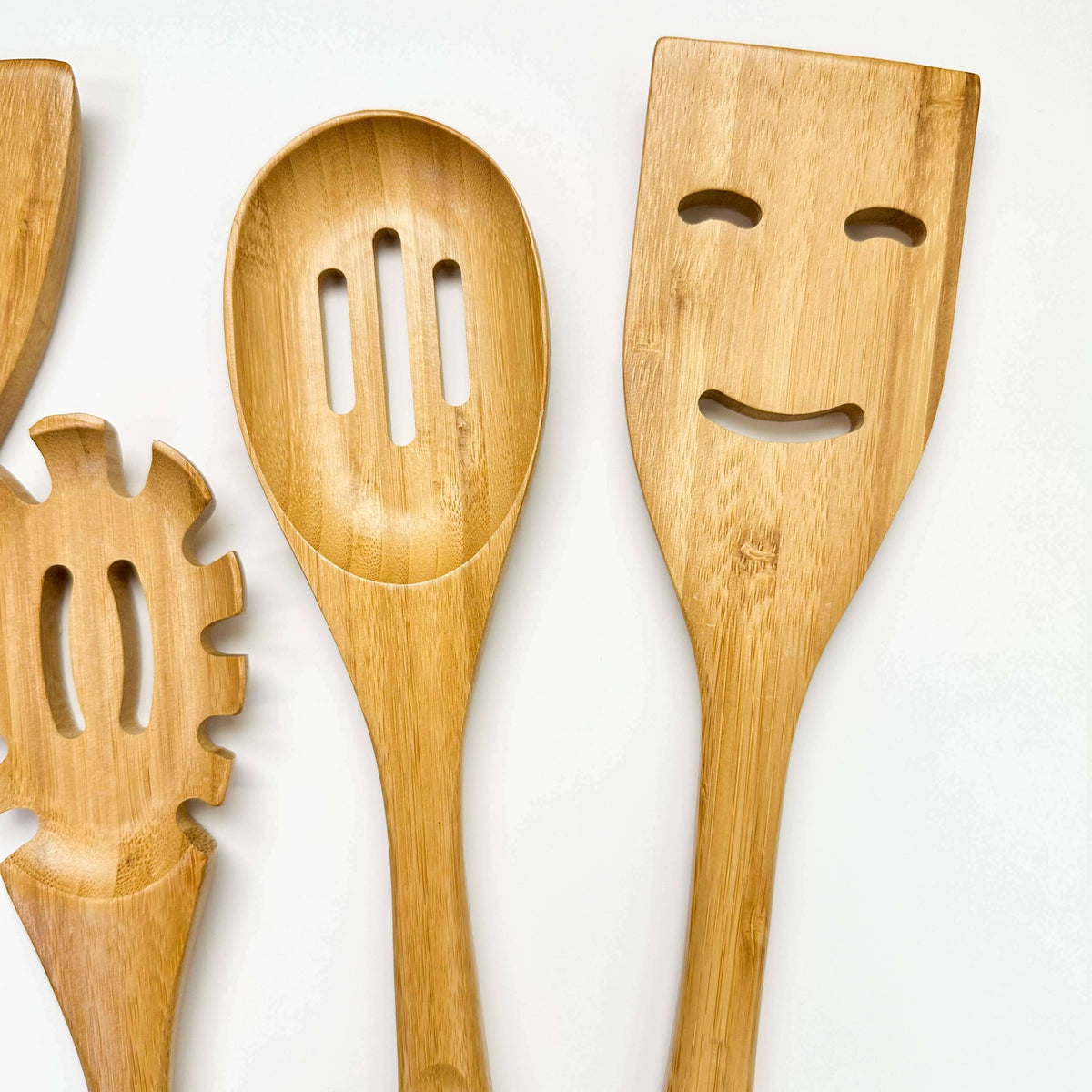 Set of wooden kitchen utensils with face designs on a white background