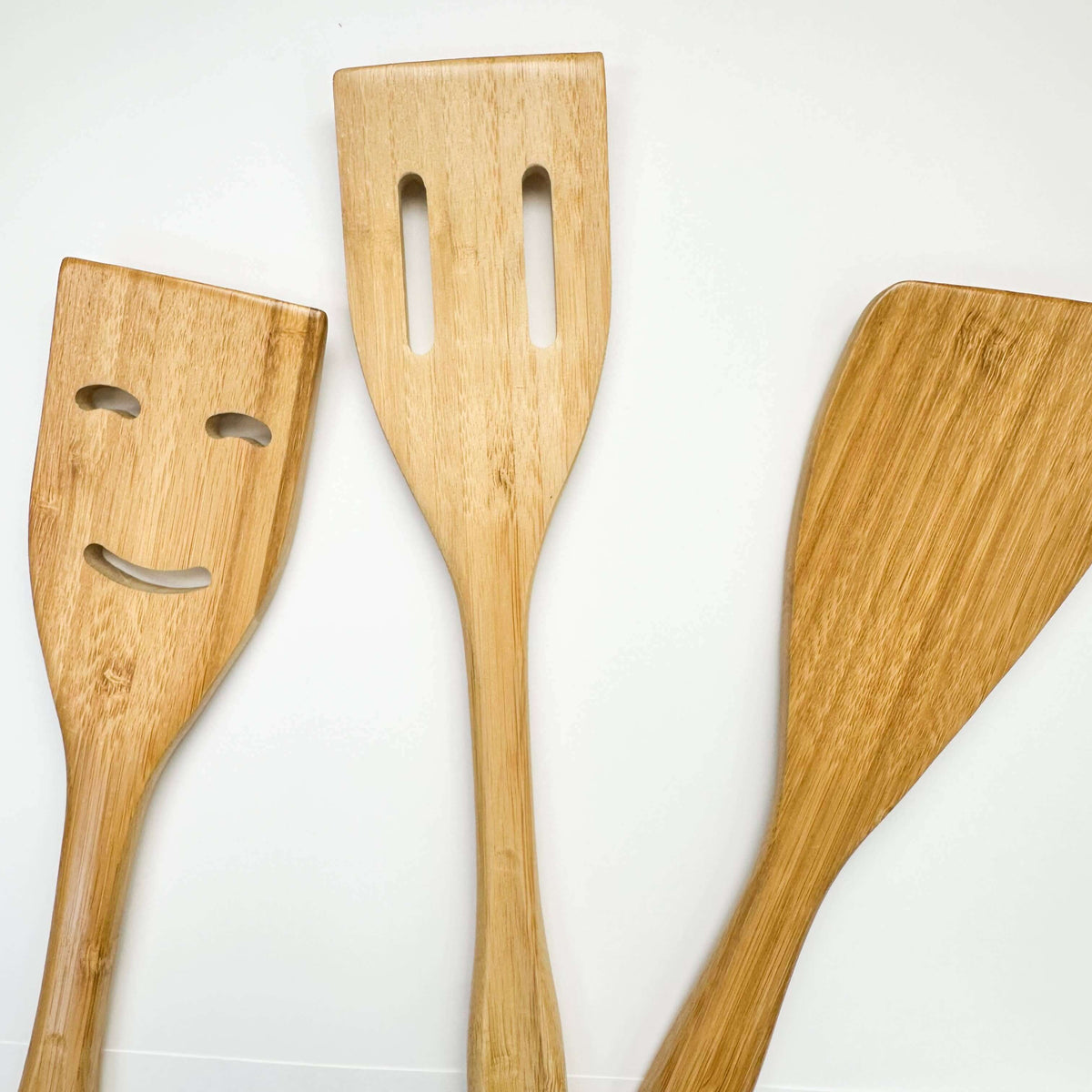Three wooden spatulas with different designs on a white background