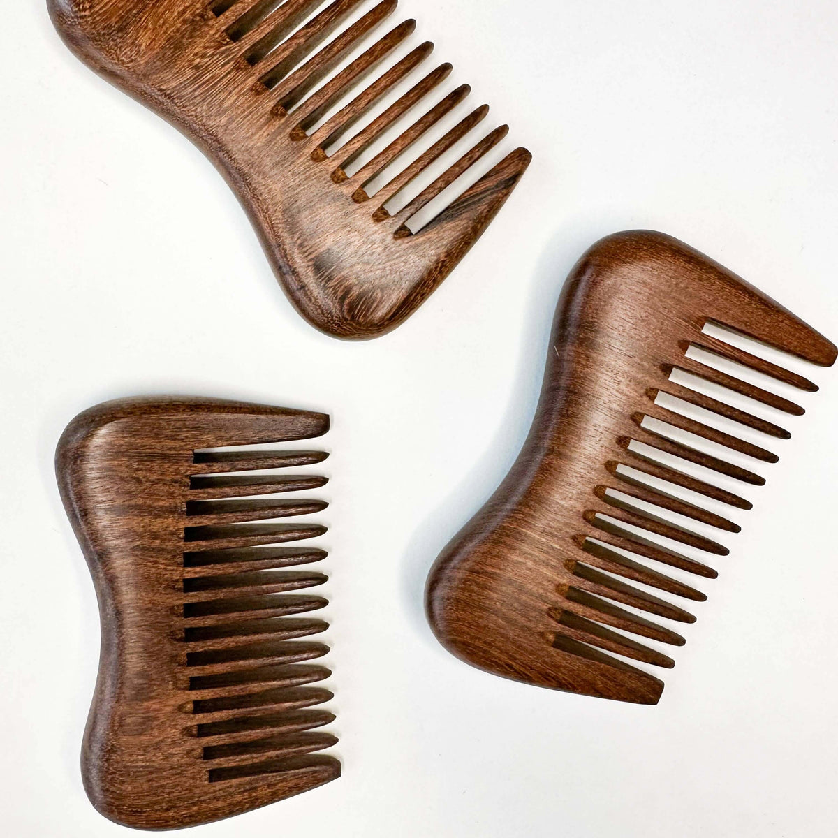 Three wooden combs on a white background