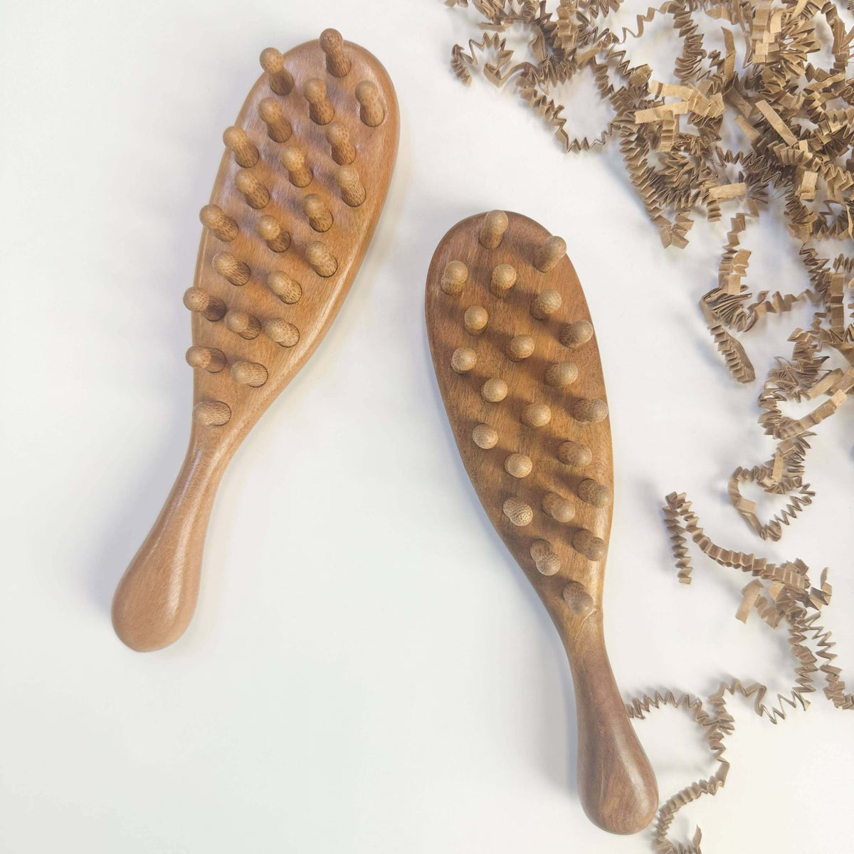 Two wooden brushes with textured handles on a light background