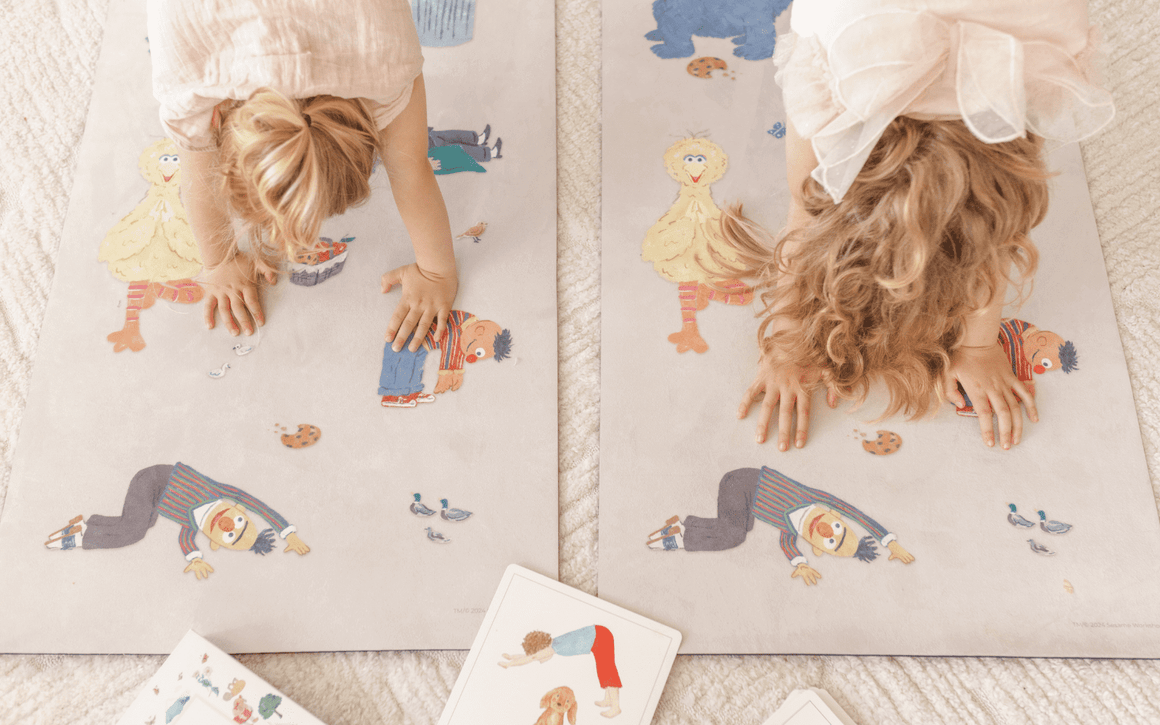 Two children playing with a puzzle on a large mat with cartoon characters.