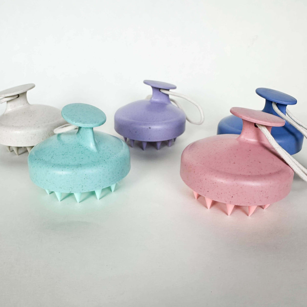 Set of five scalp massagers in different colors on a white background
