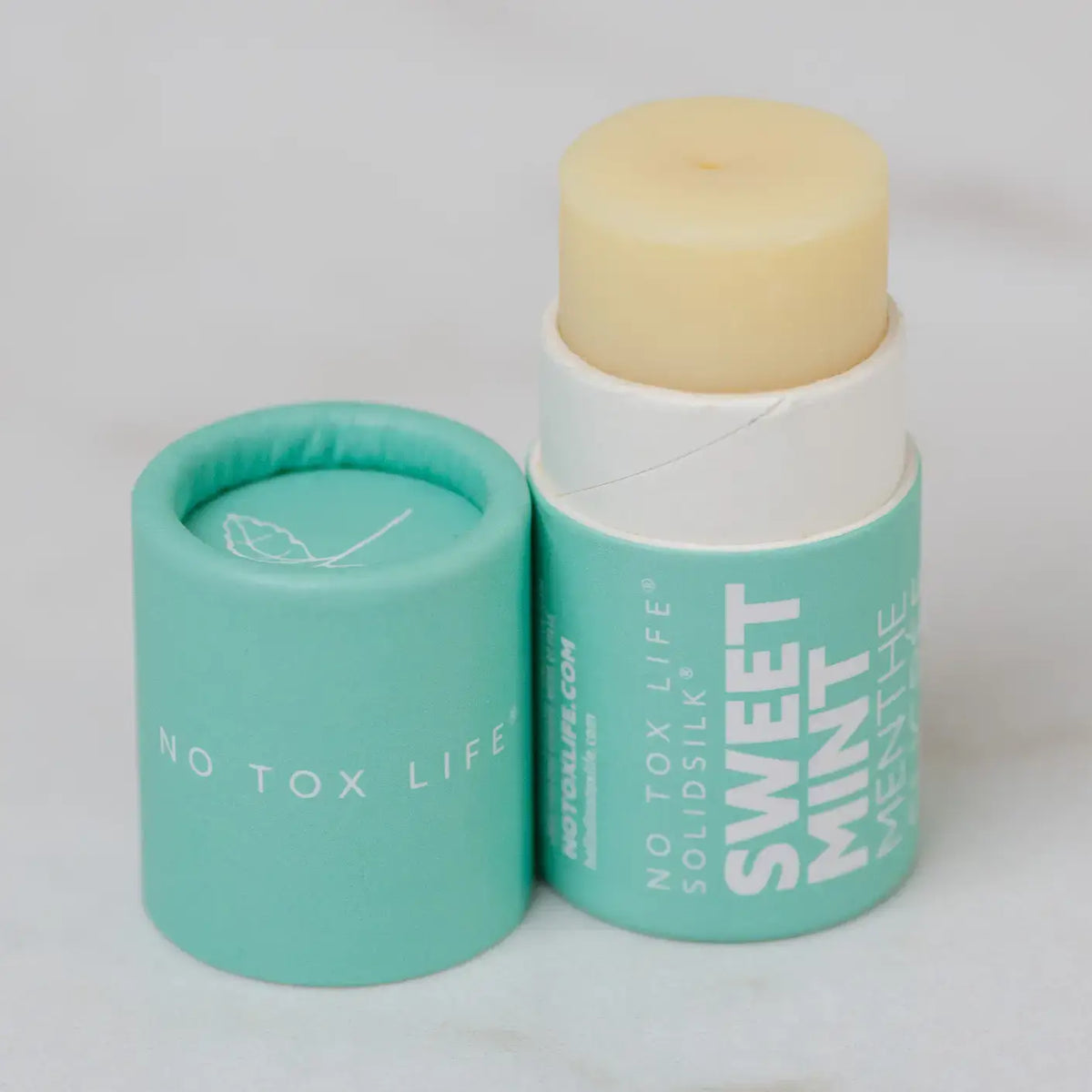 Solid mint flavor product with green container on a light gray background