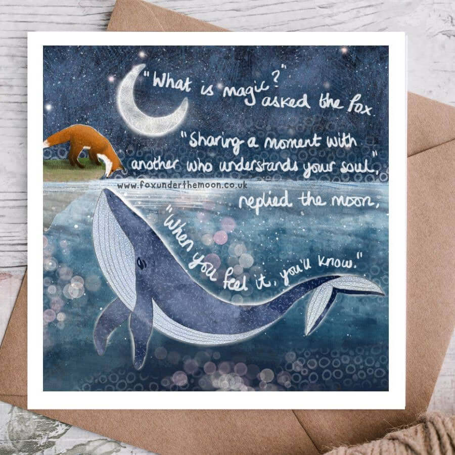 Greeting card with whale illustration and moon, featuring a quote on a wooden surface.