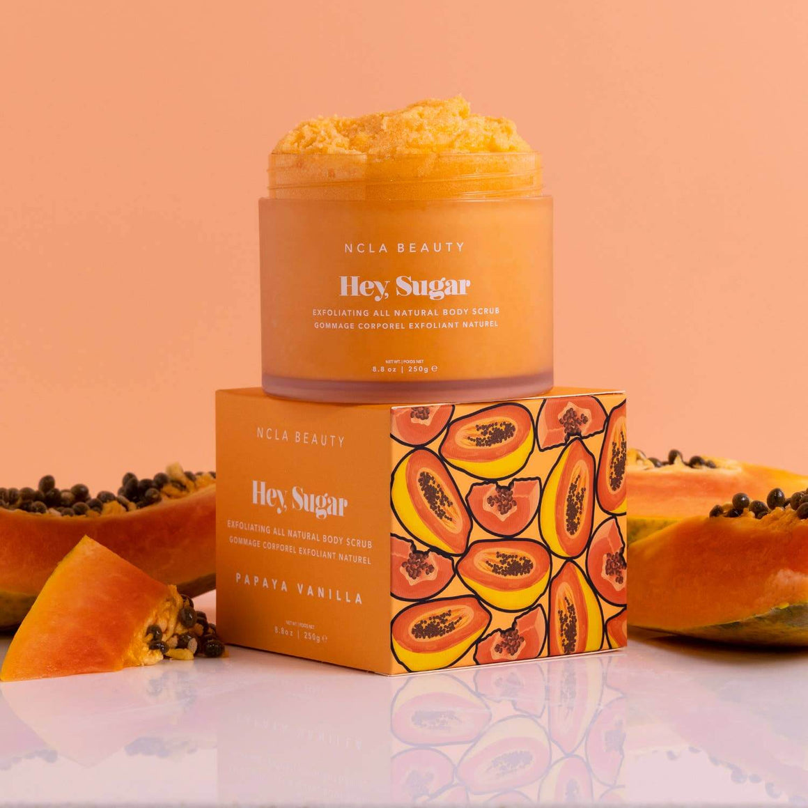 NCLA Beauty 'Hey Sugar' papaya vanilla body scrub with packaging on a peach background