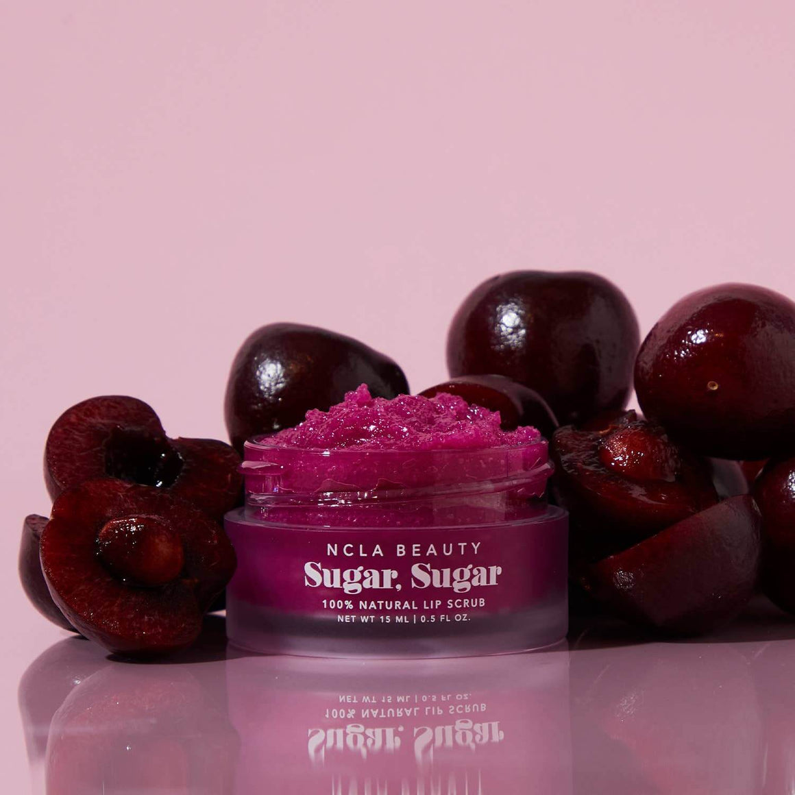 Purple lip scrub jar with cherries on a pink background