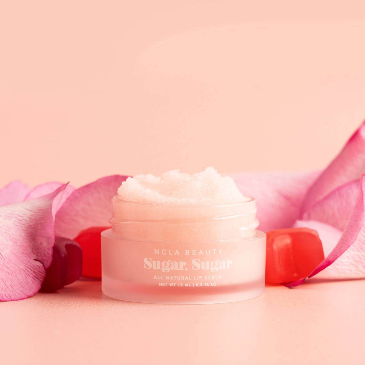 Cream jar with pink petals on a pink background