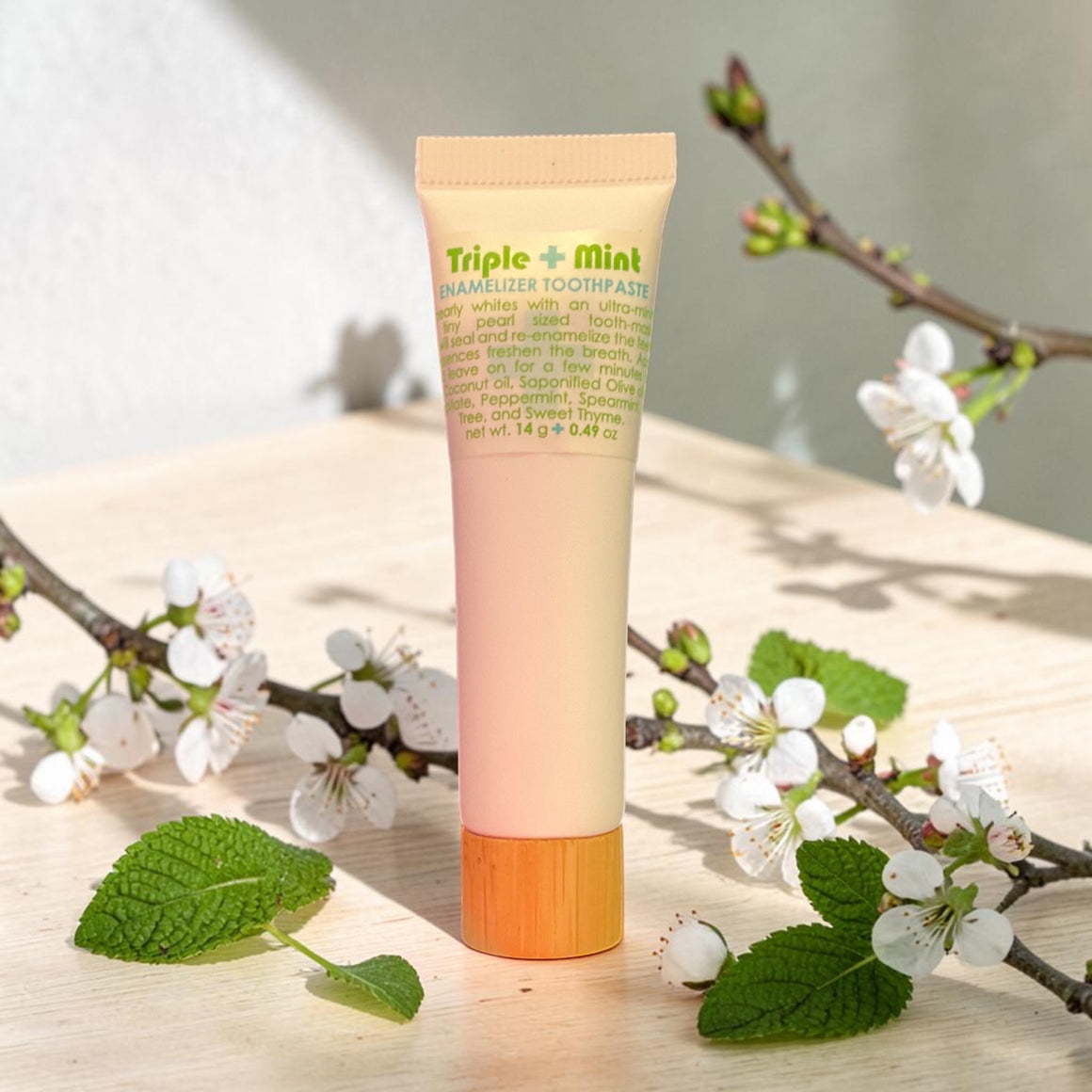 Tube of Triple Mint toothpaste on a wooden surface with floral and leaf decorations