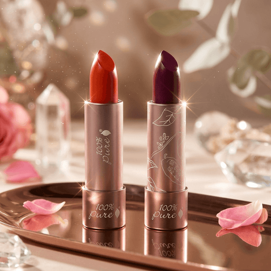 Two lipsticks on a decorative tray with flowers and crystals in the background