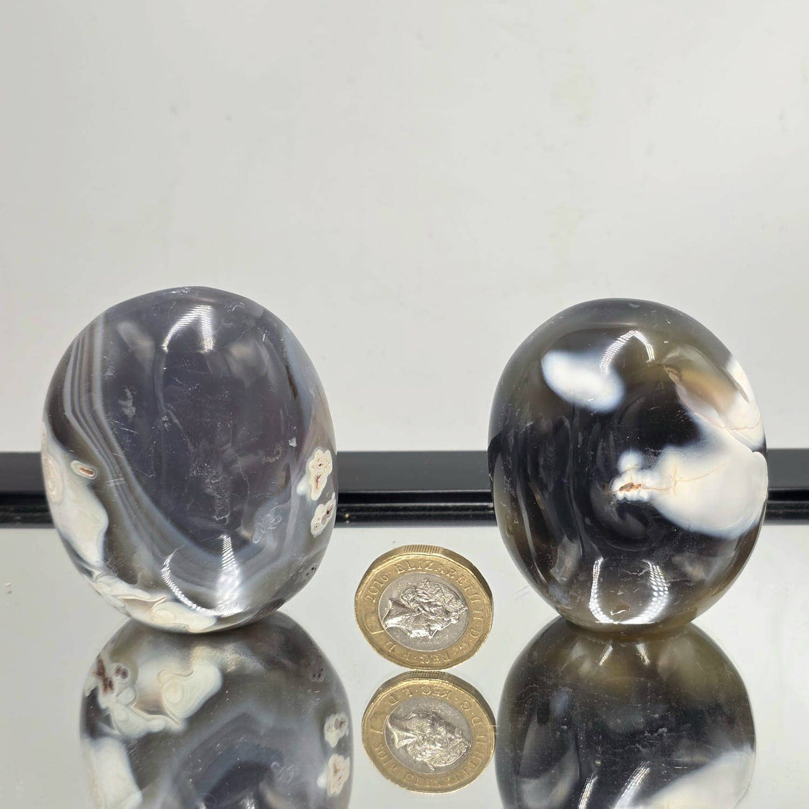 Three metallic objects on a reflective surface with coins below