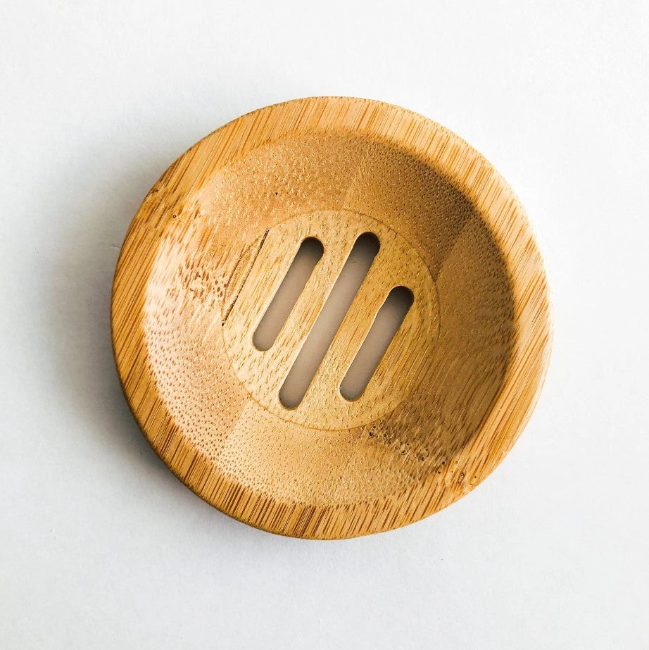 Round wooden soap dish with slotted design on a white background