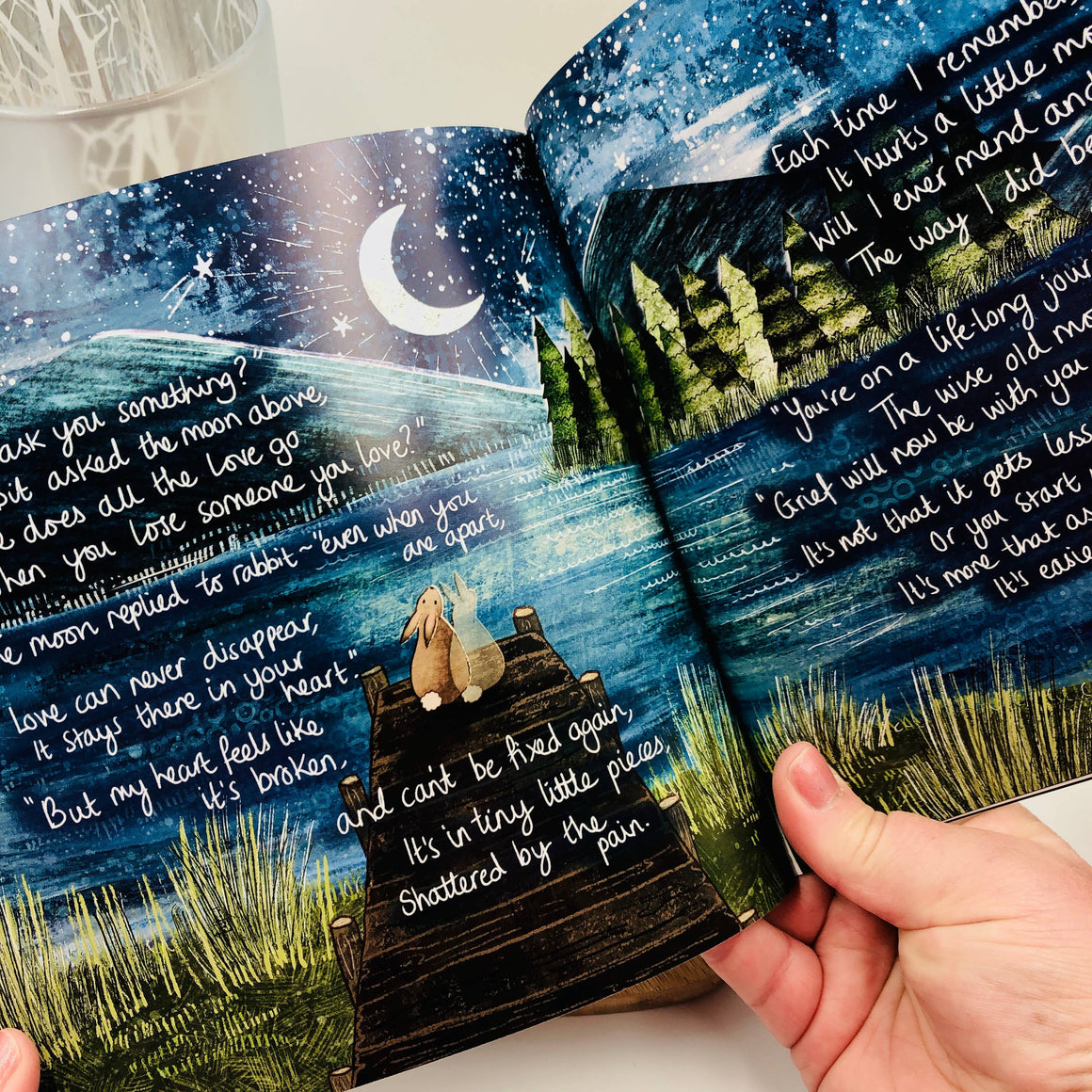 Open book with illustrations and text on a night sky and landscape.