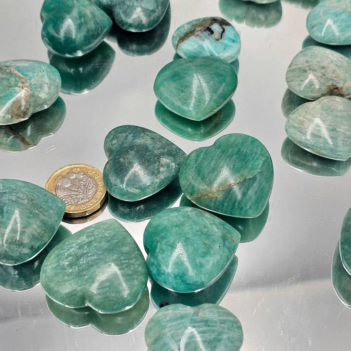 Green stones with a coin for scale on a reflective surface