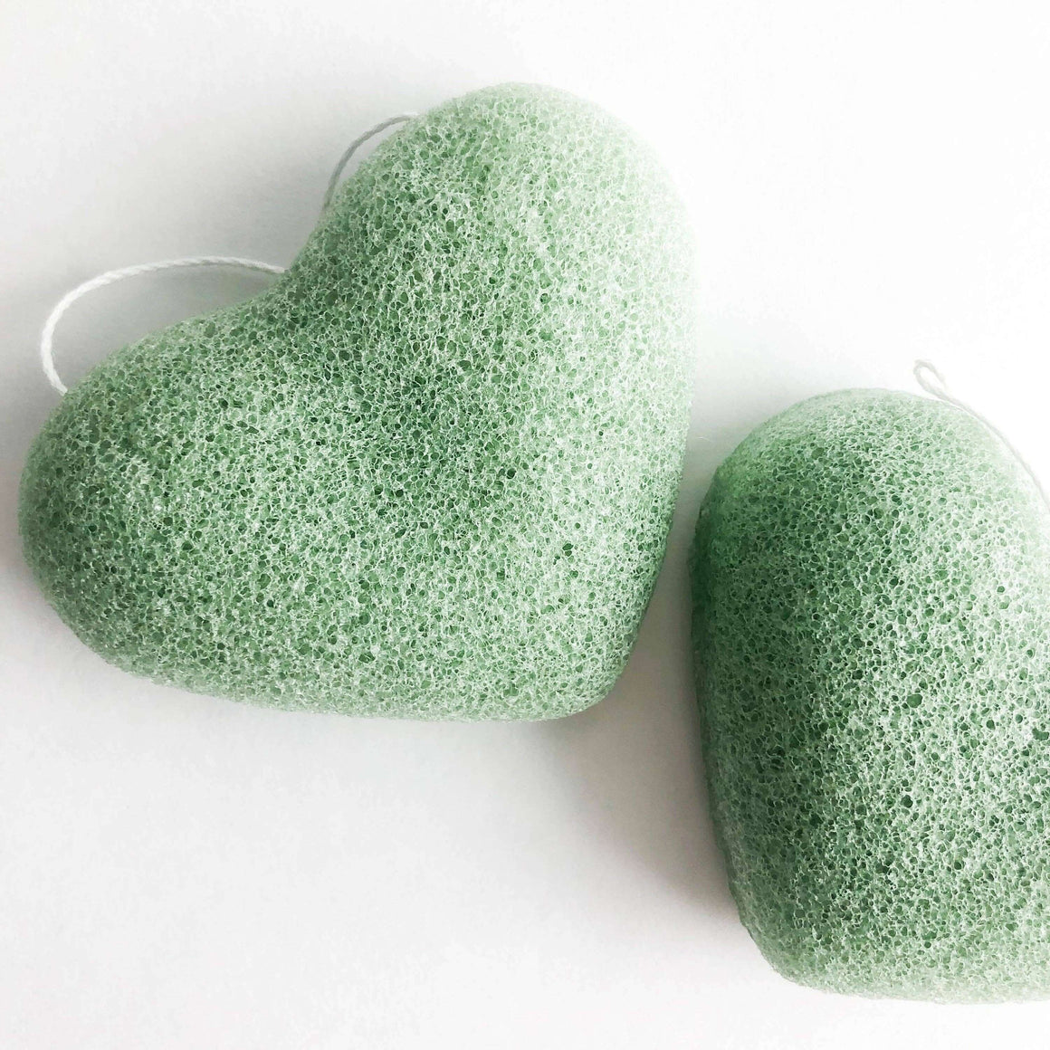 Two green konjac sponges on a white background
