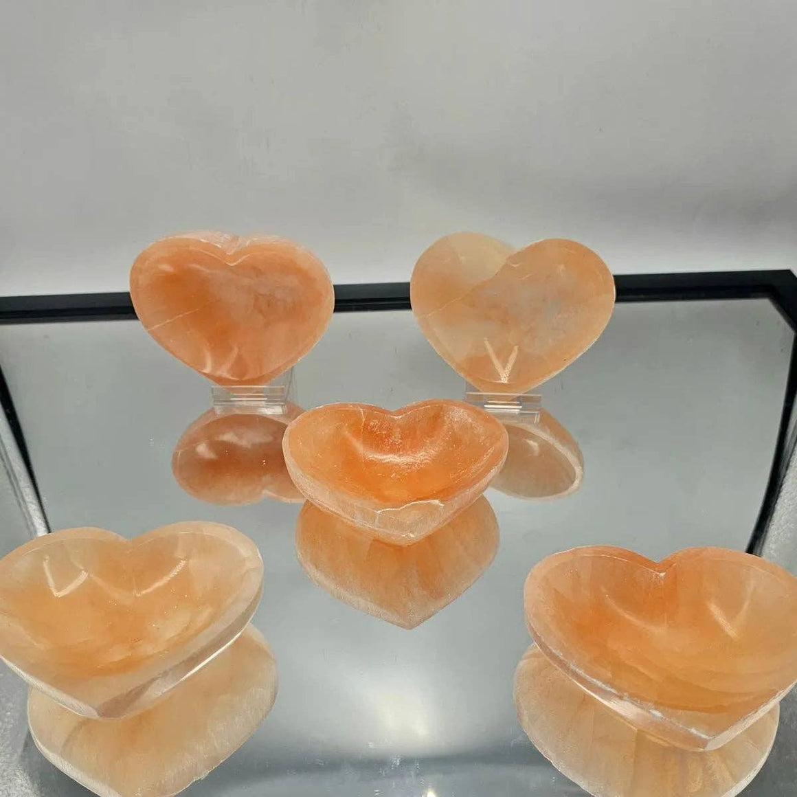 Heart-shaped objects on a reflective surface with a neutral background