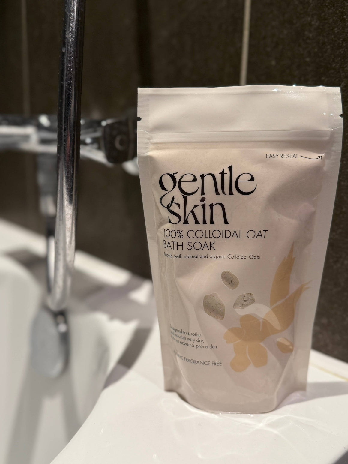 100% Organic Colloidal Oat Bath Soak package next to a bathtub faucet for soothing skin care.