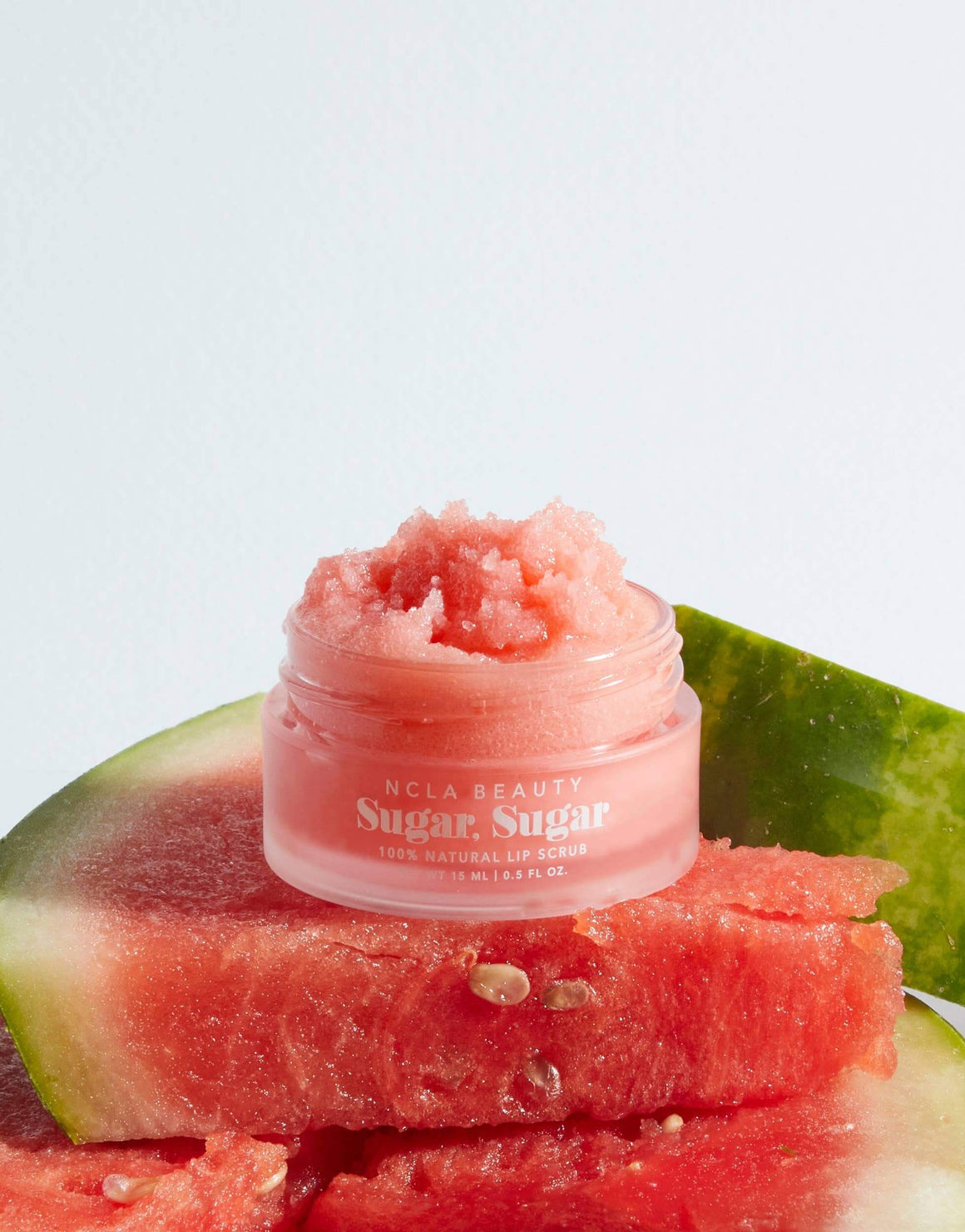 Small jar of 'Sugar Sugar' lip balm on sliced watermelon with a light blue background