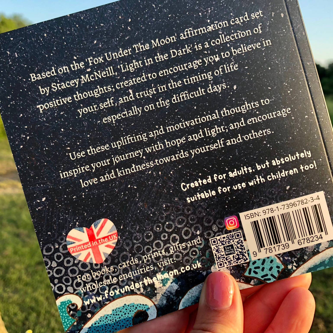 Back of a card with text and branding, held outdoors.