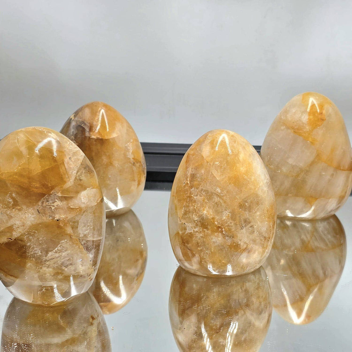 Translucent yellow stones on a reflective surface with a neutral background