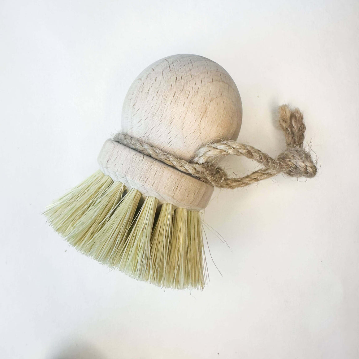 Dish brush with bristles wrapped in twine on a white background