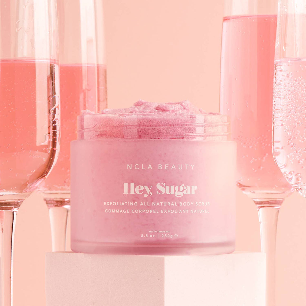 Pink jar of NCLA Beauty 'Hey Sugar' body scrub with pink background