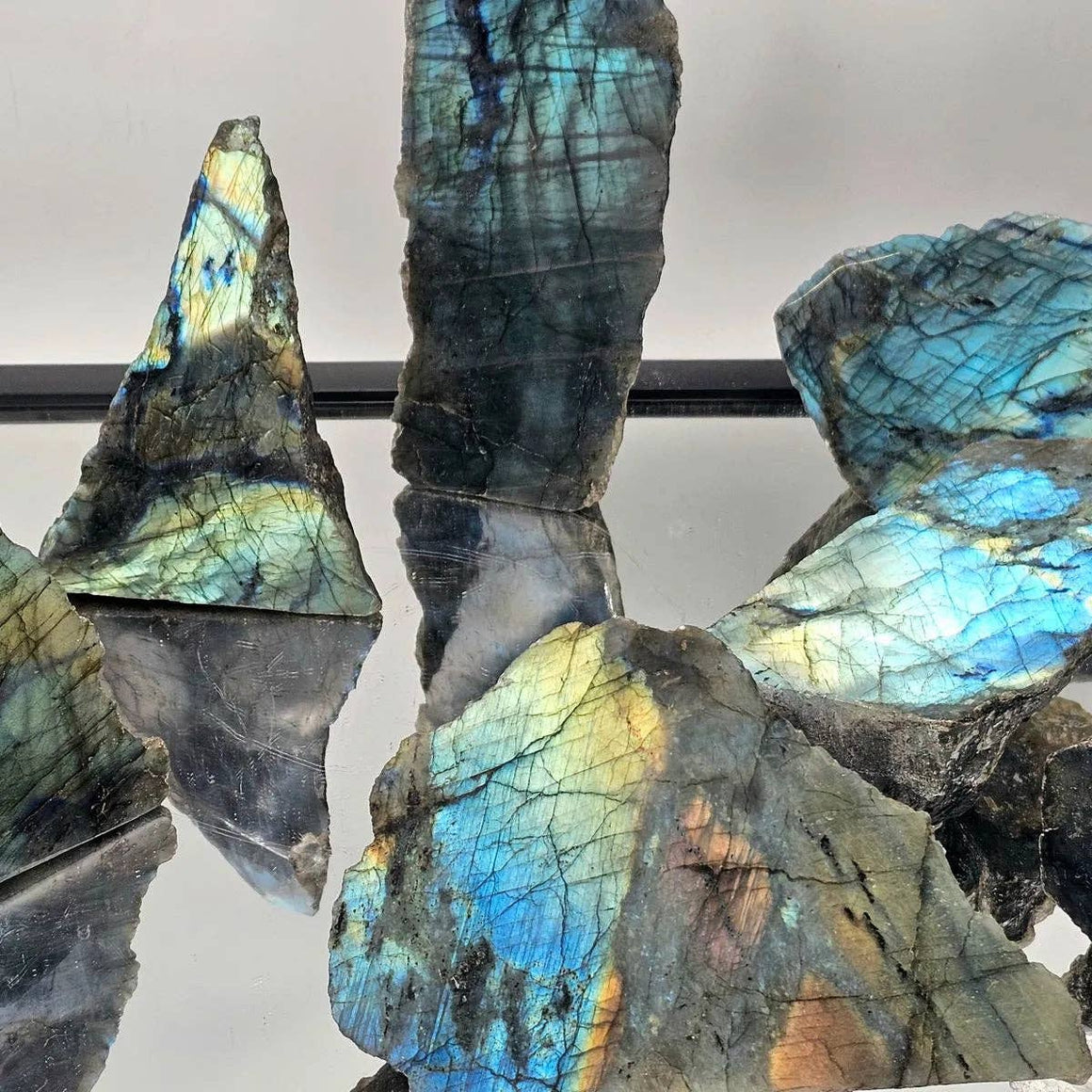 Multicolored labradorite crystals on a reflective surface with a neutral background