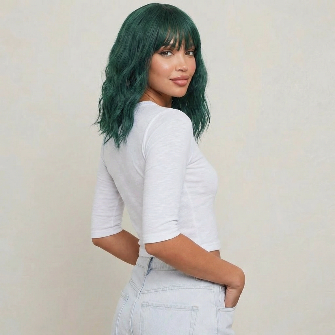 Short green wig with bangs displayed on a model, featuring wavy texture and bold emerald color.