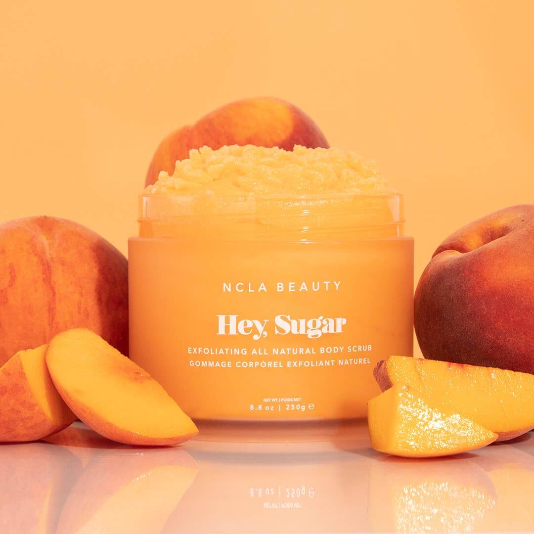NCLA Beauty 'Hey Sugar' body scrub with peaches on an orange background